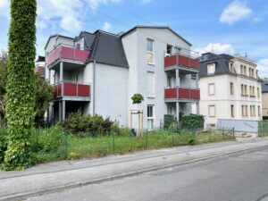 Mehrfamilienhaus mit roten Balkonen – Straßenansicht