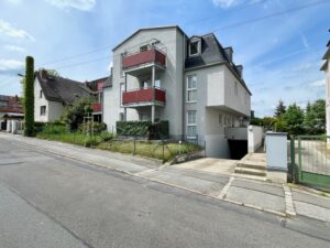 Wohngebäude mit roten Balkonen und Tiefgaragenzufahrt
