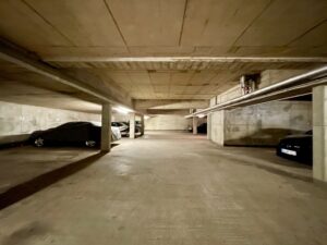 Tiefgarage mit Stellplätzen und sichtbaren Deckenleitungen