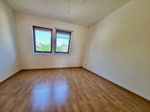 Leeres Schlafzimmer mit zwei Fenstern und Boden in Holzoptik