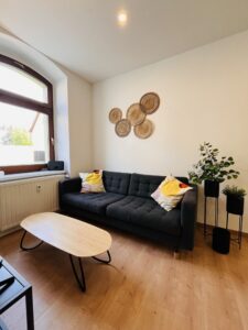 Wohnbereich mit schwarzem Sofa und ovalem Couchtisch