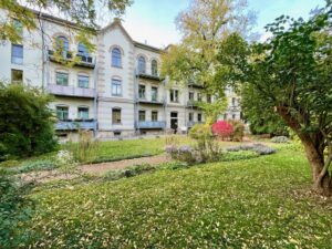 Rückseite eines Wohngebäudes mit Balkonen und angelegtem Garten