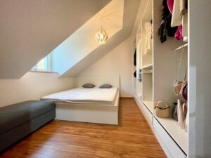Schlafbereich unter der Dachschräge mit Bett und Einbauschrank