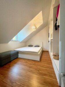 Schlafbereich unter der Dachschräge mit Bett und Einbauschrank