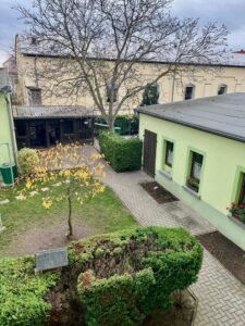 Gepflegter Innenhof mit Gartenbeeten und grünem Nebengebäude