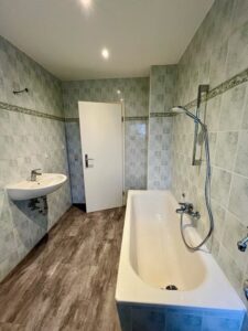 Badezimmer mit Badewanne und grauen Fliesen