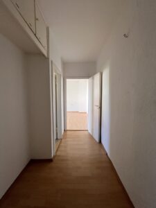Schmaler leerer Wohnungsflur mit Boden in Holzoptik