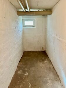 Kellerraum mit weiß gestrichenen Ziegelwänden und kleinem Fenster