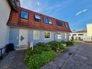 Wohnhaus mit rotem Dach, Dachfenstern und gepflastertem Hof