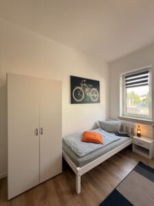 Schlafzimmer mit Einzelbett und weißem Kleiderschrank