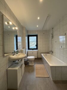 Schmales Badezimmer mit Badewanne und Fenster