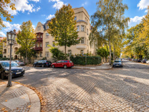 Historisches Eckhaus an einer gepflasterten Straße mit Bäumen