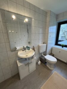 Gefliestes Badezimmer mit Waschbecken, Toilette und Fenster
