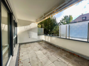 Überdachter Balkon mit Fliesenboden und Glasgeländer