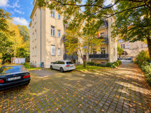Innenhof mit Bäumen, Stellplätzen und gelben Wohnhäusern