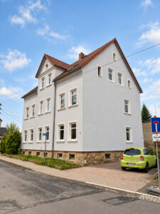 Helles Mehrfamilienhaus mit Ziergiebel – Straßenansicht